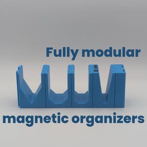 Puede incluir: Un organizador magnético modular azul. El organizador está hecho de varias secciones conectadas, cada una con un diseño en forma de V. El texto "Fully modular magnetic organizers" se muestra en azul.