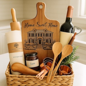 Puede incluir: Una cesta tejida llena de artículos de cocina y comedor. Incluye una tabla de cortar de madera con "Home Sweet Home" y un diseño de casa, una botella de vino, tazas medidoras, cucharas de madera, un rodillo y un tarro de mermelada. Un regalo ideal.
