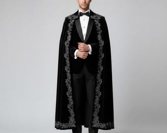 May include: A formal black velvet cape with ornate silver embroidery. The cape is worn over a black tuxedo with a bow tie. The cape's design features a detailed, swirling pattern along the edges, adding a touch of elegance to the formal attire.