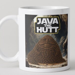 May include: White ceramic mug with a graphic of a brown, slug-like creature and the text "JAVA THE HUTT" in a yellow and black frame. The mug has a white handle and a glossy finish.