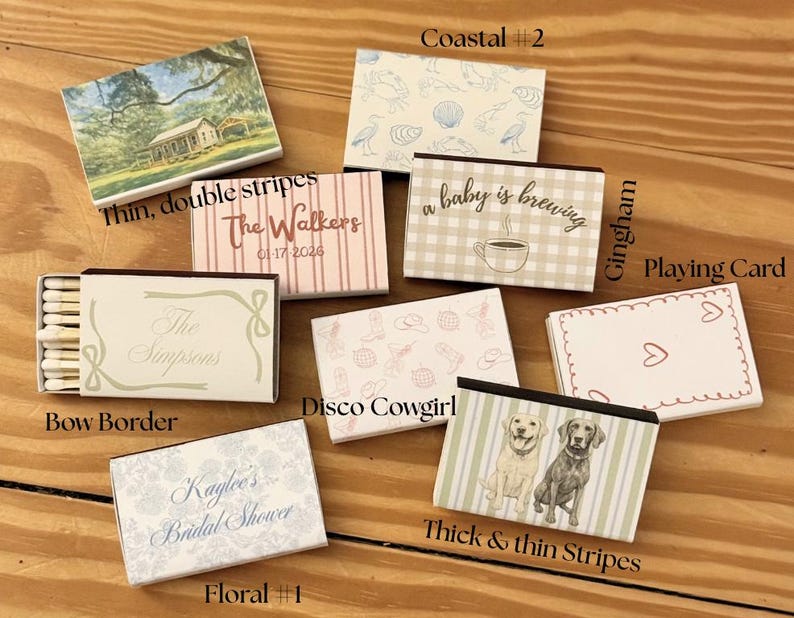 May include: A collection of decorative matchboxes with various designs. The boxes feature themes like coastal scenes, floral patterns, and text such as "The Walkers" and "Kaylee's Bridal Shower." Some boxes have illustrations of dogs, seashells, and a coffee cup.