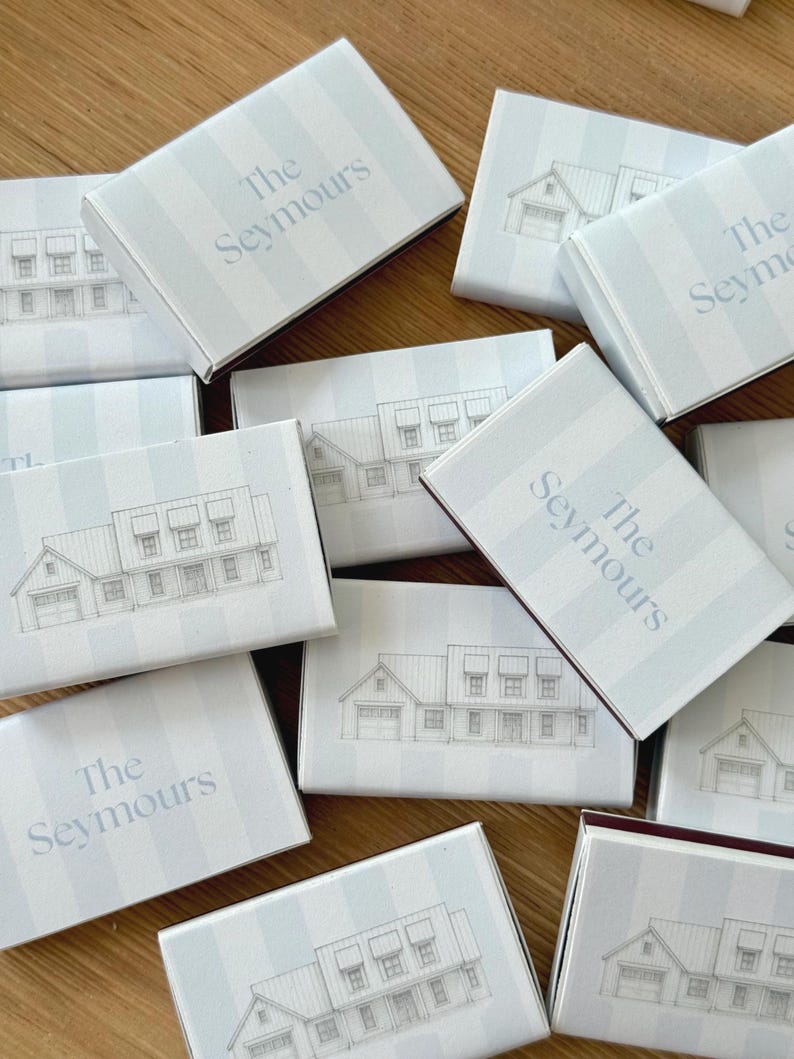 May include: A collection of light blue and white striped boxes with a house illustration and the text "The Seymours" in a soft blue font. The boxes are arranged on a wooden surface.