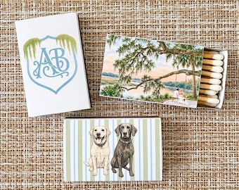 Könnte beinhalten: Drei rechteckige Streichholzschachteln mit individuellen Illustrationen. Eine Schachtel zeigt ein blaues Wappen mit den Buchstaben AB und grünem Moos. Eine andere zeigt ein Paar auf einer Schaukel unter einem Baum am Wasser.