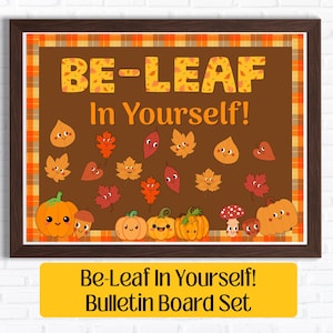May include: A rectangular bulletin board set featuring a dark brown background with the text BE-LEAF In Yourself! in yellow. The design includes various cartoon autumn leaves, pumpkins, mushrooms, and acorns, all framed by an orange plaid border.
