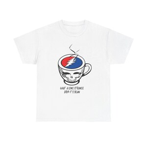 Puede incluir: Camiseta blanca con un gráfico de una taza de café con un diseño de calavera. La taza está llena de un rayo rojo y azul. El texto "WHAT A LONG STRANGE DRIP IT'S BEAN" está impreso debajo.