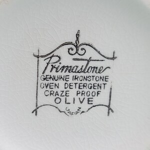 Puede incluir: Primer plano de la parte inferior de un plato de cer&aacute;mica blanco con un logotipo en blanco y negro que dice "Primastome Genuine Ironstone Oven Detergent Craze Proof Olive".