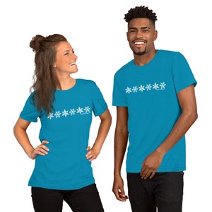 May include: Two people wearing turquoise blue t-shirts with a row of white snowflake designs. The snowflakes are stylized and have a distressed look.