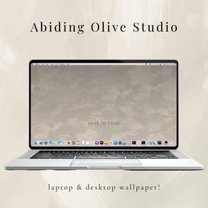 May include: A silver laptop displaying a neutral-toned desktop wallpaper with the text "rest in Him." The screen shows a cloudy sky design. The text "Abiding Olive Studio" and "laptop & desktop wallpaper!" are also visible.