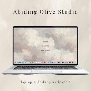 May include: A silver laptop displaying a desktop wallpaper with a cloudy, pastel-colored design. The words "make Heaven crowded" are visible on the screen. The text "Abiding Olive Studio" and "laptop & desktop wallpaper!" are also present.