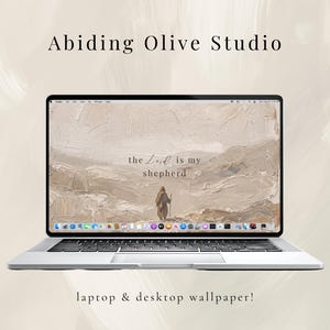 May include: A silver laptop displaying a desktop wallpaper with a beige landscape and the text "the Lord is my shepherd." The laptop is open, and the screen shows a person walking in the distance. The text "Abiding Olive Studio" and "laptop & desktop wallpaper!" are also visible.