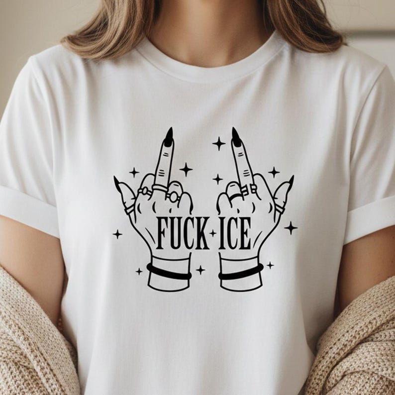 May include: White t-shirt featuring a black graphic of two hands displaying the middle finger, embellished with rings and bracelets. The text "FUCK ICE" is printed below, with star accents.