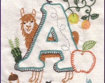 Puede incluir: Letra A bordada del alfabeto con una llama, una manzana y otros elementos inspirados en la naturaleza. La letra es blanca con un contorno turquesa y costuras marrones. La llama es marrón y tiene la cara blanca. La manzana es roja con una hoja verde. El fondo es blanco.