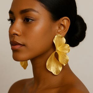 Puede incluir: Pendientes dorados llamativos con diseño floral. Los pendientes tienen una superficie texturizada y una forma de tres pétalos, creando un look audaz y elegante. Un accesorio llamativo para ocasiones especiales.