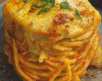 Può includere: Una porzione di spaghetti ricoperta di formaggio fuso e salsa di pomodoro, guarnita con erbe verdi fresche. Il piatto di pasta è presentato su un piatto blu, presentando un pasto rustico e appetitoso.