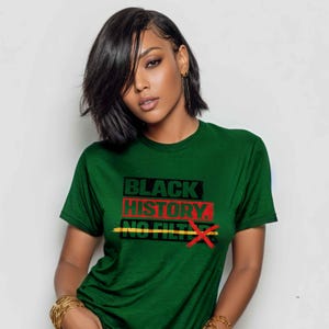 May include: A green t-shirt with the text "BLACK HISTORY. NO FILTER." in black, red, and yellow. The text is centered on the chest. The shirt is being worn.
