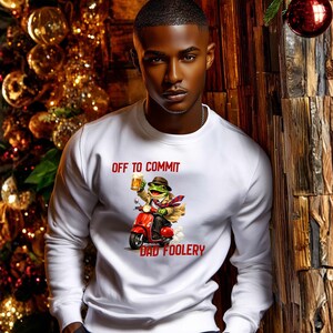 Op de afbeelding: Wit sweatshirt met de rode tekst "OFF TO COMMIT BAD FOOLERY". De afbeelding toont een kikker met hoed en jas op een rode scooter, die een biertje vasthoudt. Een casual, leuk ontwerp.