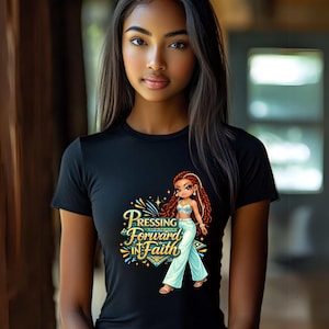 May include: Black t-shirt featuring a graphic of a cartoon woman with long red braids and the text "Pressing Forward in Faith." The woman is wearing a light blue outfit. The design includes gold and blue accents.