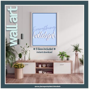 Puede incluir: Un cuadro rectangular enmarcado en blanco con fondo azul claro y el texto Everything hallelujah en letras cursivas blancas. La lámina se muestra en una pared sobre un mueble multimedia de madera con puertas de armario blancas.