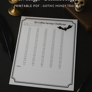 May include: A printable PDF titled "50 Coffin Savings Challenge" with a gothic theme. The design features coffin shapes for tracking savings, a bat graphic, and the text "Gothic Money Tracker". A lit candle, skull, and feather pen are also visible.