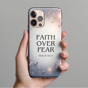 May include: A phone case with a floral design and the words "FAITH OVER FEAR" and "PSALM 56:3" in black. The case has a gradient background of white, gray, and gold.