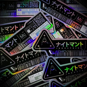 May include: A collection of black and holographic stickers with Japanese text and geometric designs. The stickers feature the text "NIGHTMANT INDUSTRIES", along with barcodes, QR codes, and the word "RADIOACTIVE".