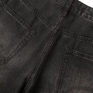 May include: A pair of black denim jeans featuring a faded wash, a high-rise waistband with belt loops, and two back pockets. The fabric displays a textured weave with visible stitching along the seams and pockets, showcasing a classic five-pocket construction.