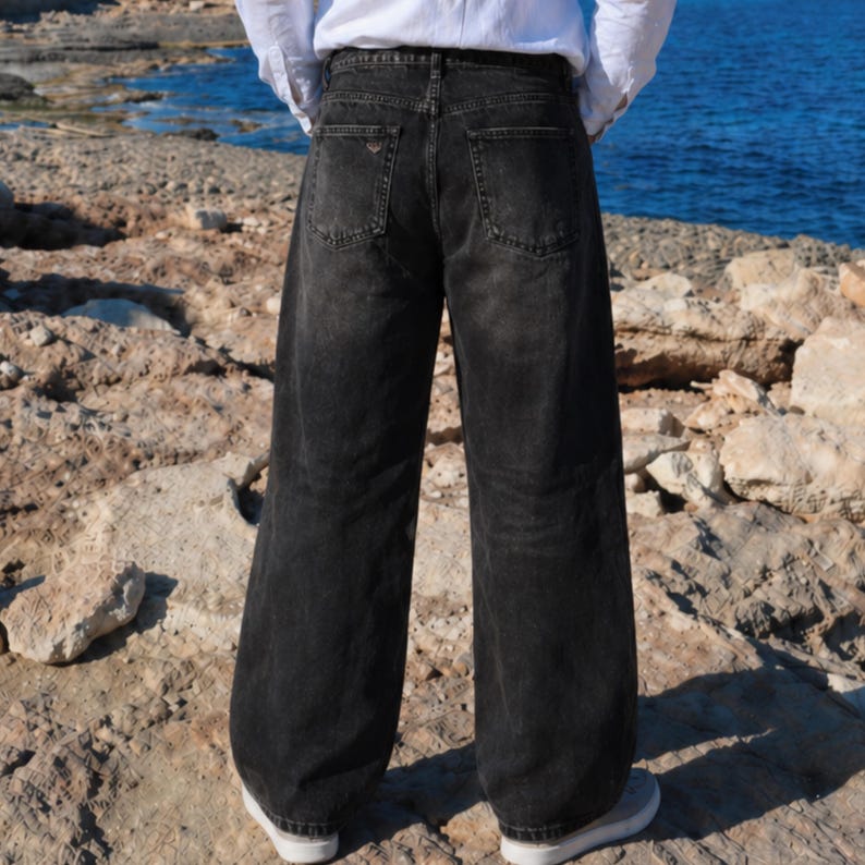 May include: A pair of loose-fitting, high-waisted black denim jeans with a faded wash. The jeans feature a classic five-pocket design, including two back pockets with visible stitching, a waistband with belt loops, and a straight-leg silhouette.
