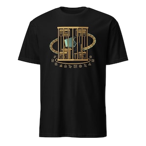 Puede incluir: Camiseta negra con un diseño dorado que representa a una persona trabajando en un ordenador dentro de una jaula. El diseño incluye servidores, un anillo de símbolos de datos y otros iconos tecnológicos. La camiseta está hecha de un material suave y cómodo.