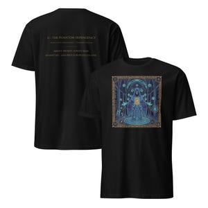 May include: Black t-shirt with a detailed graphic of a robed figure with a glowing center, surrounded by ornate designs in blue, gold, and teal. The back of the shirt displays text: "II - THE PHANTOM DEPENDENCY" and other phrases.