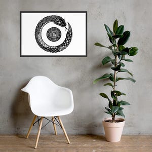 Puede incluir: Impresión artística enmarcada en blanco y negro con un diseño de Ouroboros, una serpiente que se come su propia cola. La obra de arte se muestra sobre un fondo blanco. Una silla blanca y una planta en maceta están en primer plano.