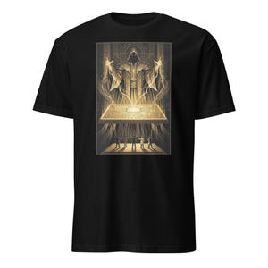 May include: Black t-shirt with a detailed graphic. The graphic shows a robed figure with outstretched hands above a glowing circuit board, with smaller figures below. The design is in shades of gold and beige.