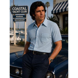May include: A light blue short-sleeved knit shirt with a pointed collar, a single chest pocket, and white buttons, paired with dark navy trousers and a black leather belt with a gold buckle. The shirt features a textured fabric finish.