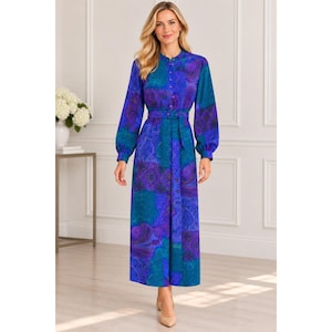 May include: A long-sleeved midi dress in shades of blue, purple, and teal with a repeating paisley pattern. The dress features a mandarin collar, a full-length front button placket, and a matching fabric belt with a buckle at the waist.