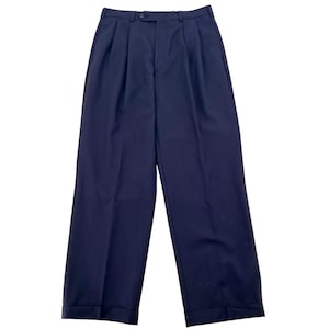 May include: A pair of dark navy blue trousers featuring a high-waisted design with double pleats at the front, a button closure at the waistband, a zippered fly, and straight legs that finish with a cuffed hem at the bottom of each pant leg.
