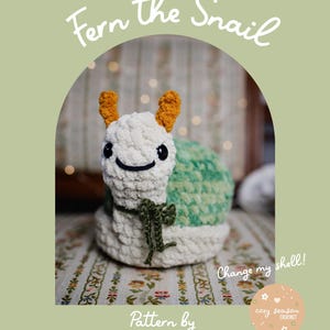 May include: A crocheted snail toy, named "Fern the Snail", with a white body, green shell, and orange antennae. The image includes the text "Change my shell!" and "Pattern by Cozy Season Crochet".