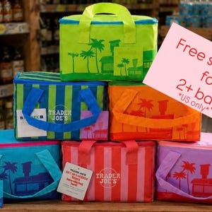 May include: A collection of colorful insulated tote bags with handles, featuring tropical designs and the Trader Joe's logo. The bags are in various colors, including green, blue, orange, red, and purple. Each bag has a matching small square bag.
