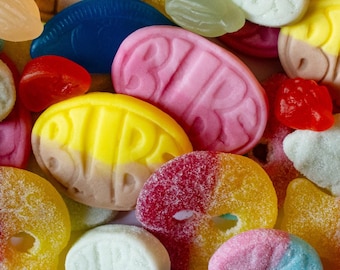 May include: A colorful assortment of gummy candies in various shapes and colors. The image features candies in shades of red, yellow, pink, blue, and white. Some candies have the word "BIR" on them. The candies are arranged closely together, creating a vibrant and appealing display.