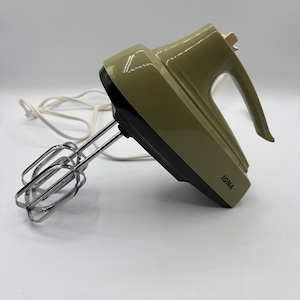 Peut inclure: Un batteur électrique à main vert olive et noir avec un cordon d'alimentation blanc et deux fouets chromés. L'appareil dispose d'une poignée sur le dessus, d'un interrupteur de vitesse et de la marque IONA imprimée en noir sur la base.