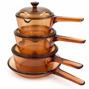Peut inclure: Une pile de quatre ustensiles de cuisine en verre ambré, comprenant trois casseroles de tailles différentes et un couvercle assorti. Chaque pièce présente une longue poignée en verre intégrée et une finition lisse et translucide.