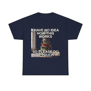 Peut inclure: T-shirt bleu marine avec le texte "I HAVE NO IDEA HOW THIS WORKS SO PLEASE DO NOT TOUCH IT". Le graphisme présente une pile de composants électroniques colorés. Le t-shirt est fait d'une matière douce et confortable.