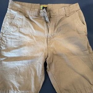 以下が含まれることがあります： カーキ色のショートパンツ。複数のポケットとボタン留めが付いています。 ショーツはクラシックなデザインで、ステッチが見え、丈夫な生地です。 ショーツは青い面に平らに置かれています。