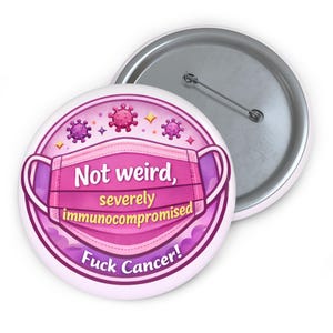 May include: A white button badge with a pink and purple design. The design features a pink face mask, virus illustrations, and the text "Not weird, severely immunocompromised Fuck Cancer!"
