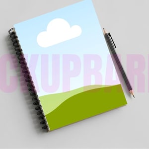 Puede incluir: Cuaderno de espiral con un diseño de paisaje que presenta un cielo azul, una nube blanca y colinas verdes. Un lápiz negro descansa sobre el cuaderno. La encuadernación en espiral del cuaderno es negra.