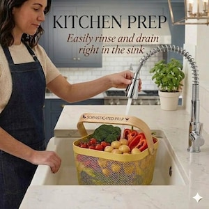 May include: A yellow mesh colander basket with a light wood handle featuring the text SOPHISTICATED PREP. The basket is filled with fresh produce including broccoli, red bell peppers, and potatoes, positioned under a chrome kitchen faucet.