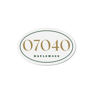 May include: Oval-shaped white sign with the number "07040" in gold and the word "Maplewood" in green. The sign has a green border.