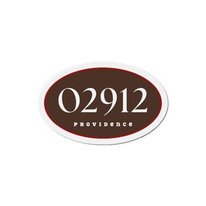 May include: An oval sticker with a white border and a thin red inner border. The center is brown with the white numbers "02912" and the word "PROVIDENCE" in white text below the numbers.