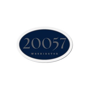 May include: An oval sticker with a navy blue centre and a white border. The number "20057" is printed in grey, with "washington" printed below it in a smaller font. The sticker is on a white background.