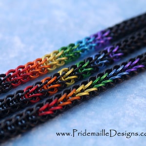 May include: Four colorful chainmail bracelets with a rainbow color gradient. The bracelets are made of black and colored metal rings. The bracelets are arranged in a row, with the most colorful bracelet at the top and the least colorful bracelet at the bottom. The bracelets are on a blue background.