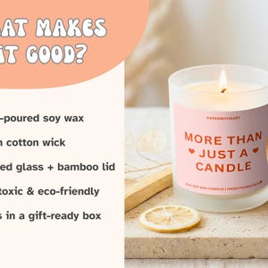 May include: A lit candle in a frosted glass jar with a bamboo lid. The label reads "More Than Just a Candle." The candle is on a stone surface with a dried lemon slice. The text on the image says "Hand-poured soy wax."