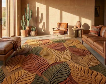 May include: A large area rug with a leaf design in shades of brown, green, and yellow. The rug is placed in a living room with a leather sofa, chair, and potted cacti. The room has a warm, inviting atmosphere.